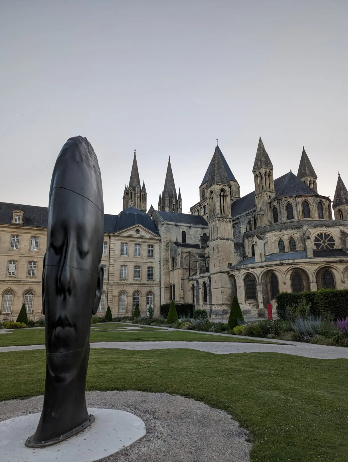 Sculpture noire en forme de visage allongé posée dans le jardin