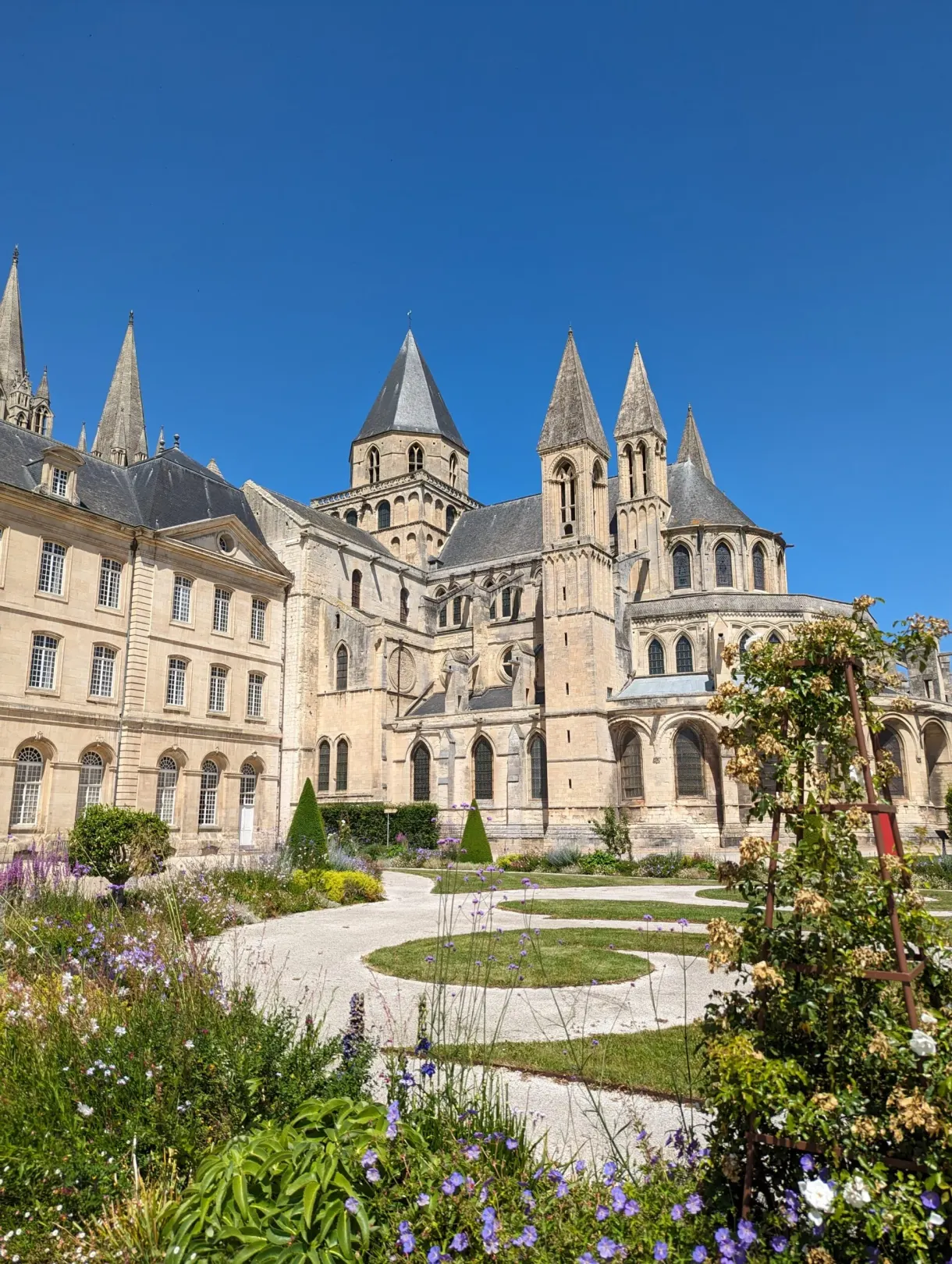 Chevet de l'abbatiale dressé au-dessus des massifs fleuris
