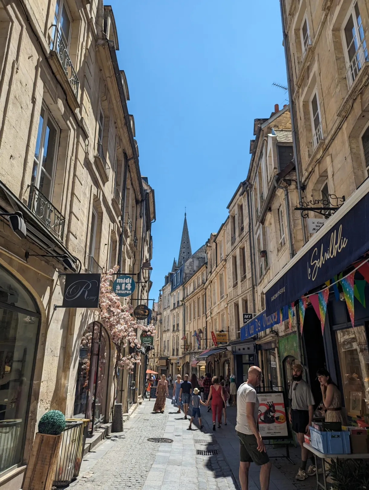 Rue piétonne commerçante animée montant vers un clocher