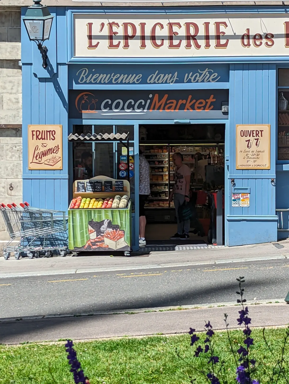 Devanture bleue d'une épicerie de quartier et son étal de fruits