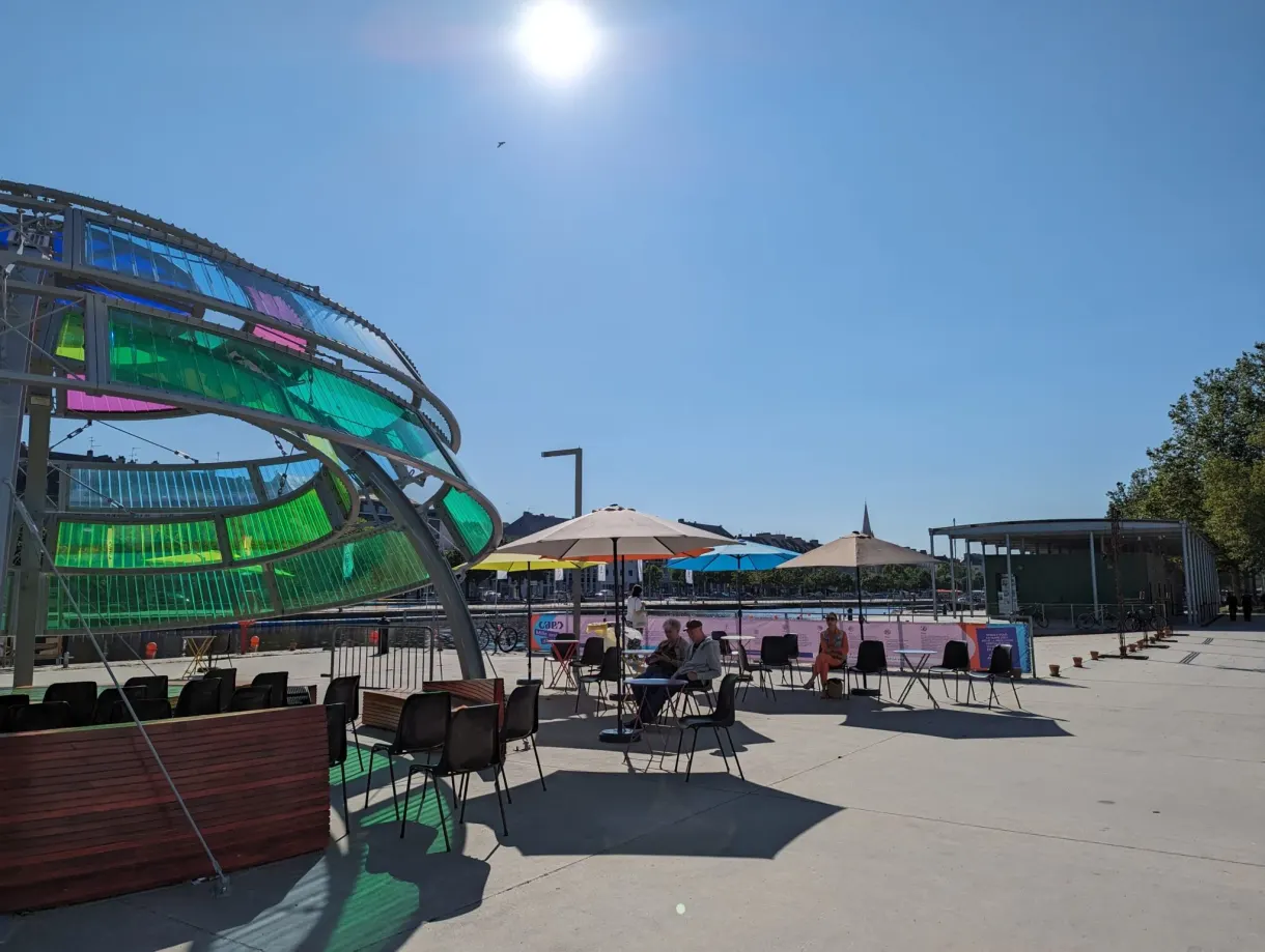 Terrasse d'été aux parasols colorés sous une structure de verre vert