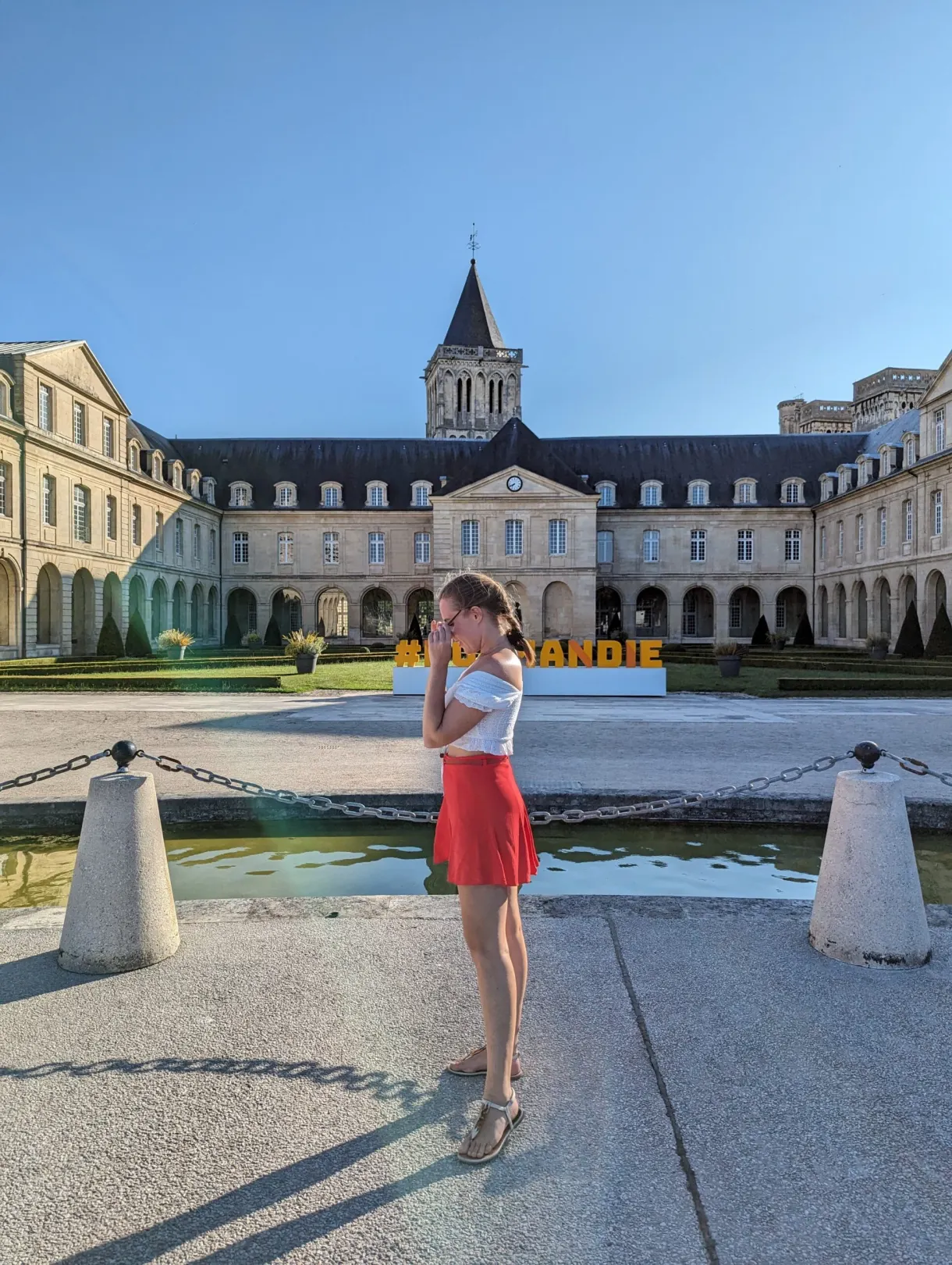 Lettres jaunes Normandie dans la cour, visiteuse en jupe rouge