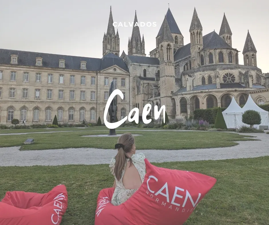 Visiteuse assise sur des coussins roses face à l'Abbaye aux Hommes