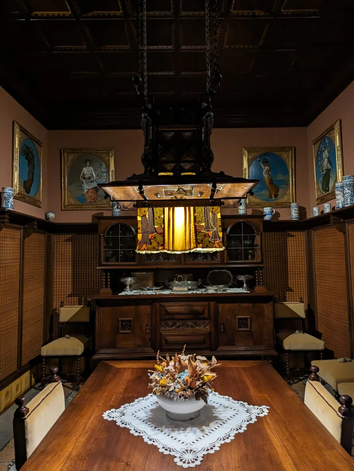 Salle à manger boisée au lustre de verre et murs rose pâle