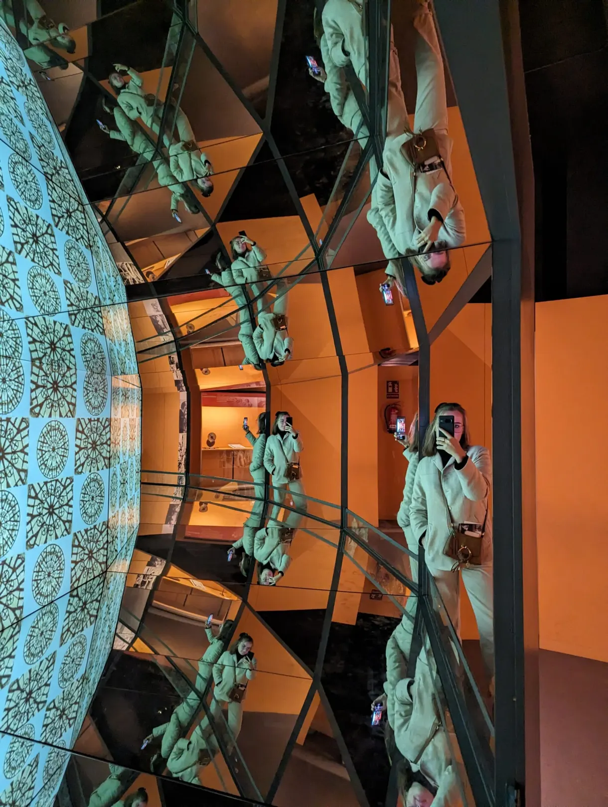Jeu de miroirs multipliant le reflet d'une visiteuse en vert