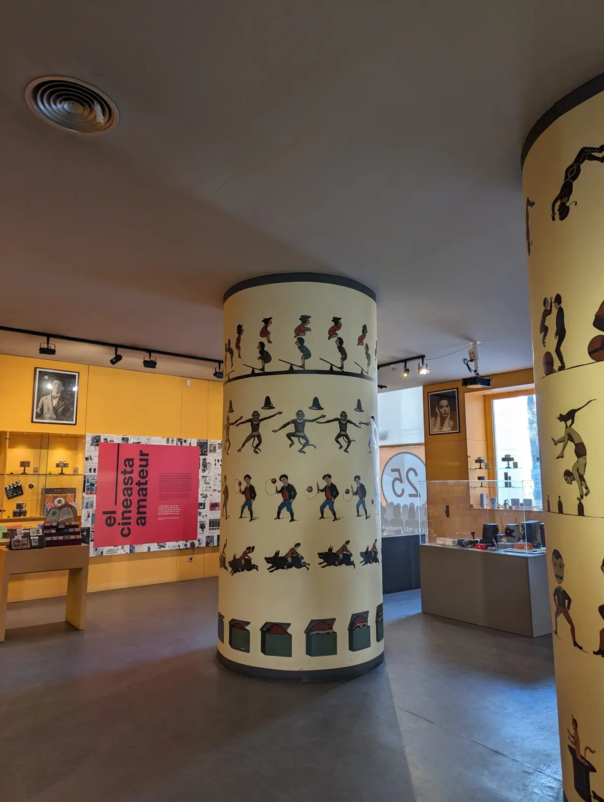 Colonnes jaunes ornées de silhouettes animées, salle El cineasta amateur