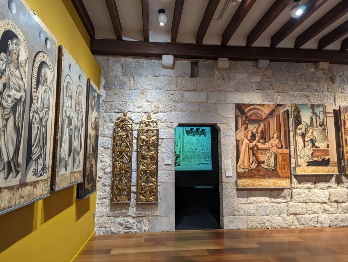 Retables peints et bas-reliefs accrochés à un mur de pierre claire