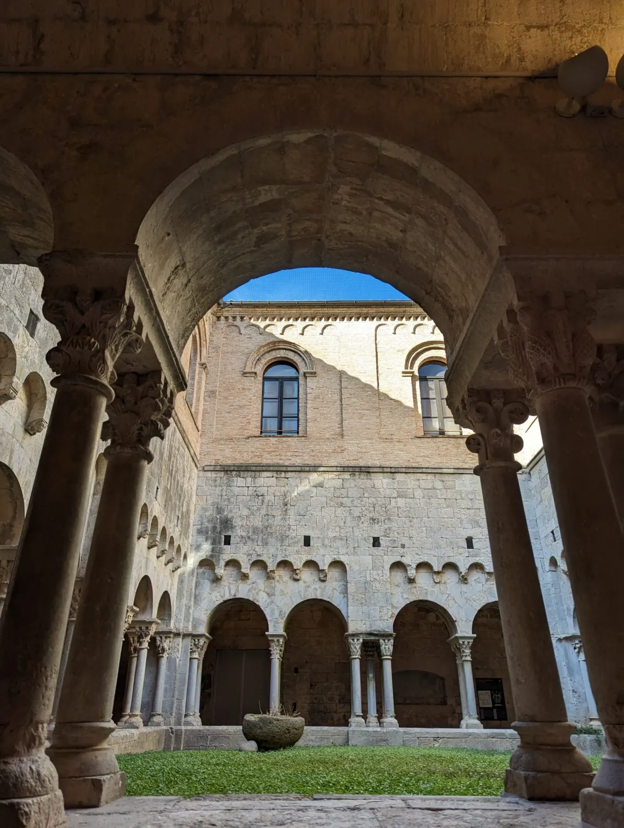 Cloître roman aux chapiteaux sculptés ouvert sur un ciel bleu