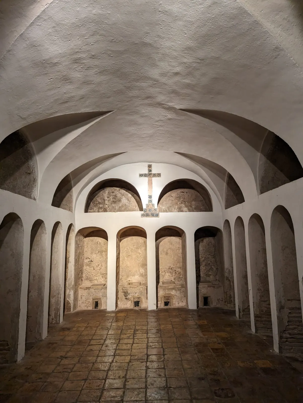 Salle voûtée blanchie aux niches en arcades et croix murale