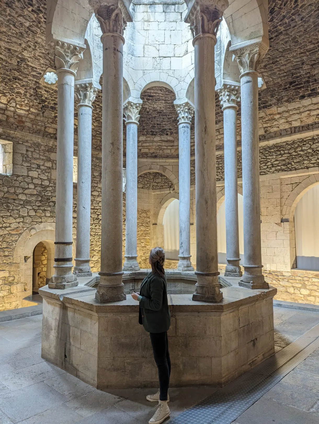 Visiteuse observant la vasque centrale ceinte de colonnes claires
