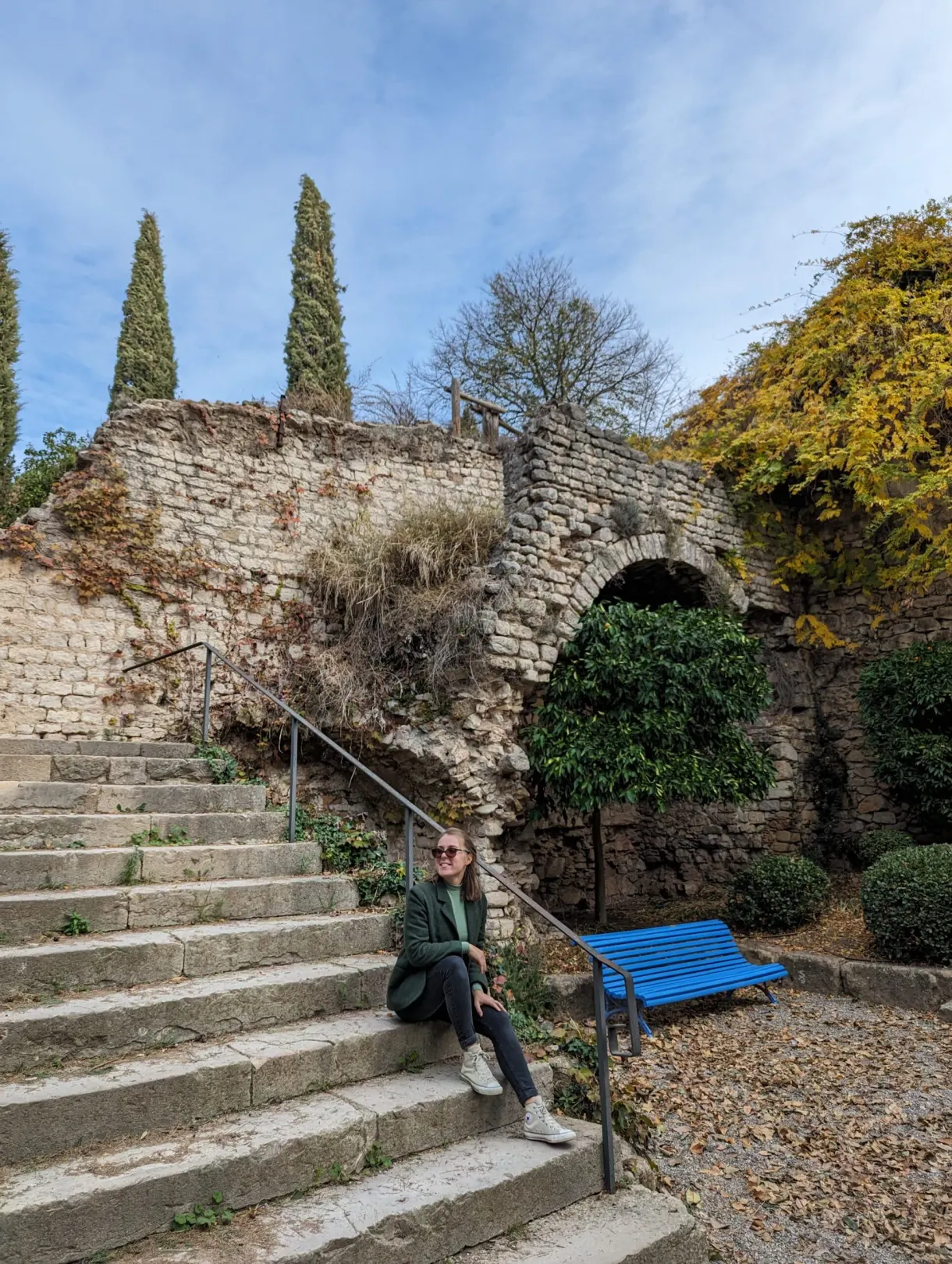 Femme assise sur un escalier de pierre près d'un banc bleu