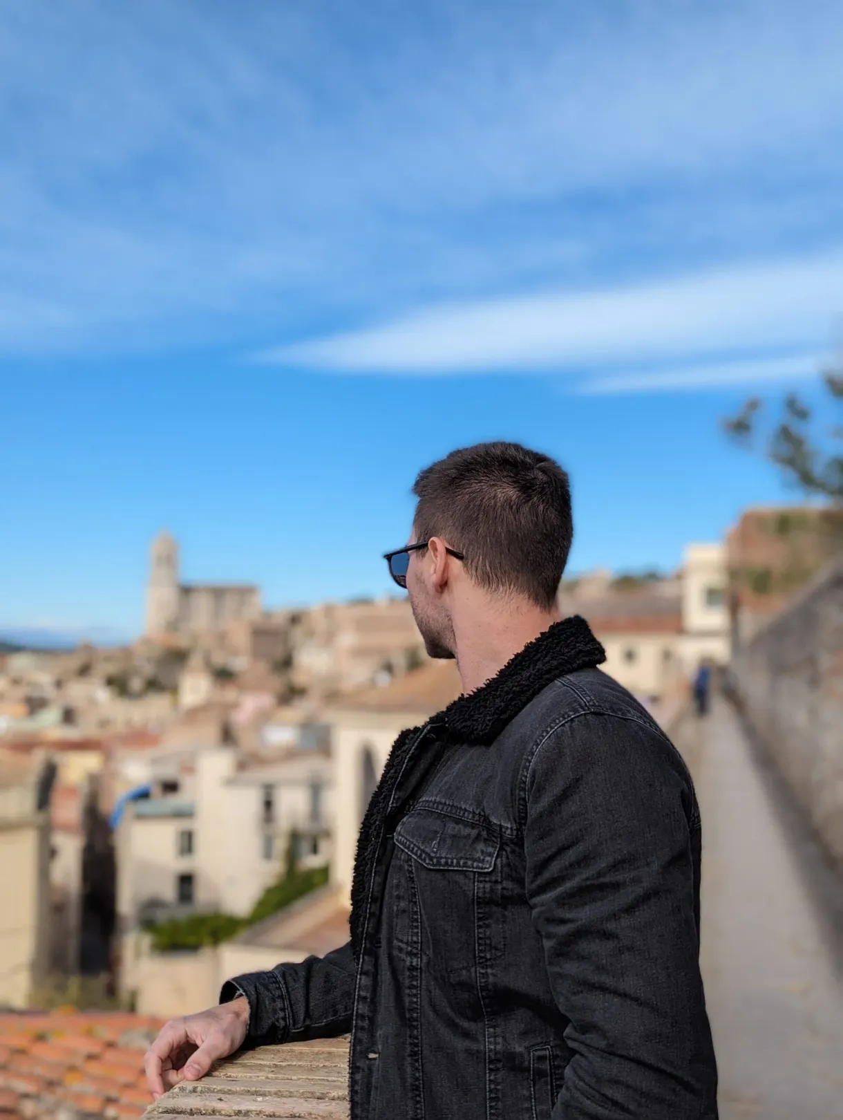Homme de profil accoudé au parapet devant les toits de Gérone