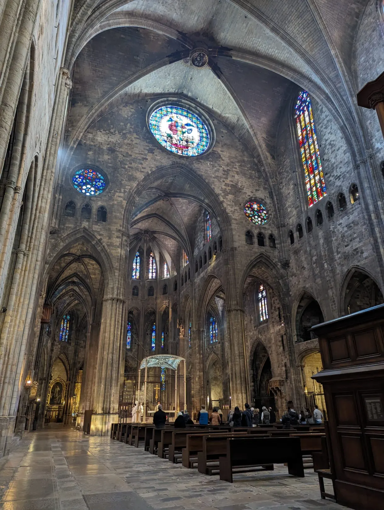 Nef gothique aux rosaces et vitraux colorés, fidèles assis
