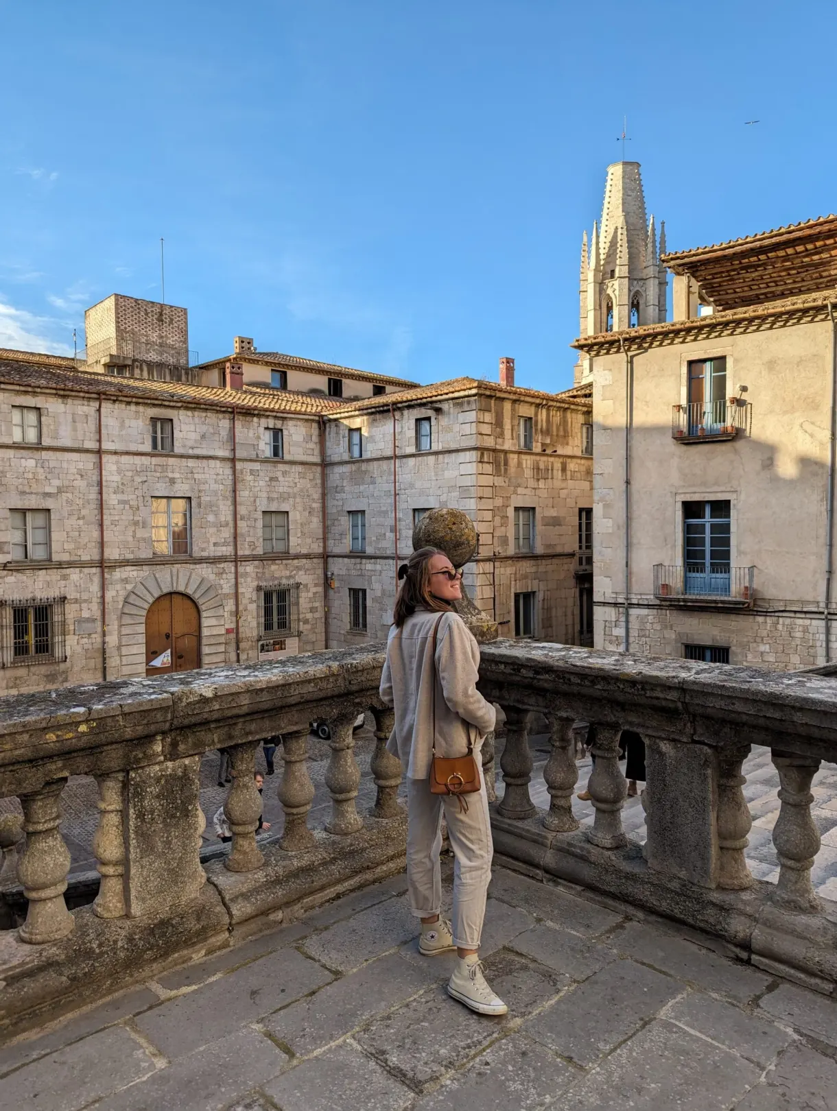 Femme accoudée à une balustrade de pierre face aux façades dorées
