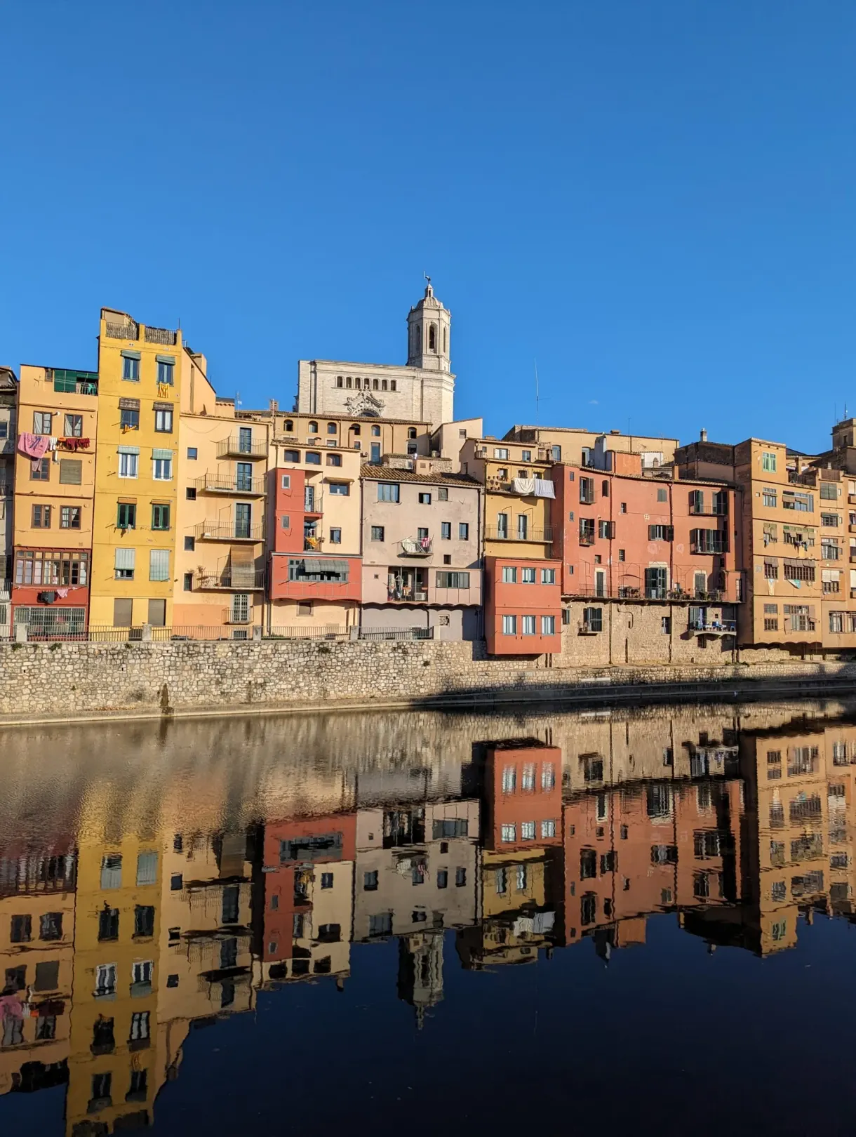 Façades jaunes et roses de l'Onyar reflétées dans l'eau calme