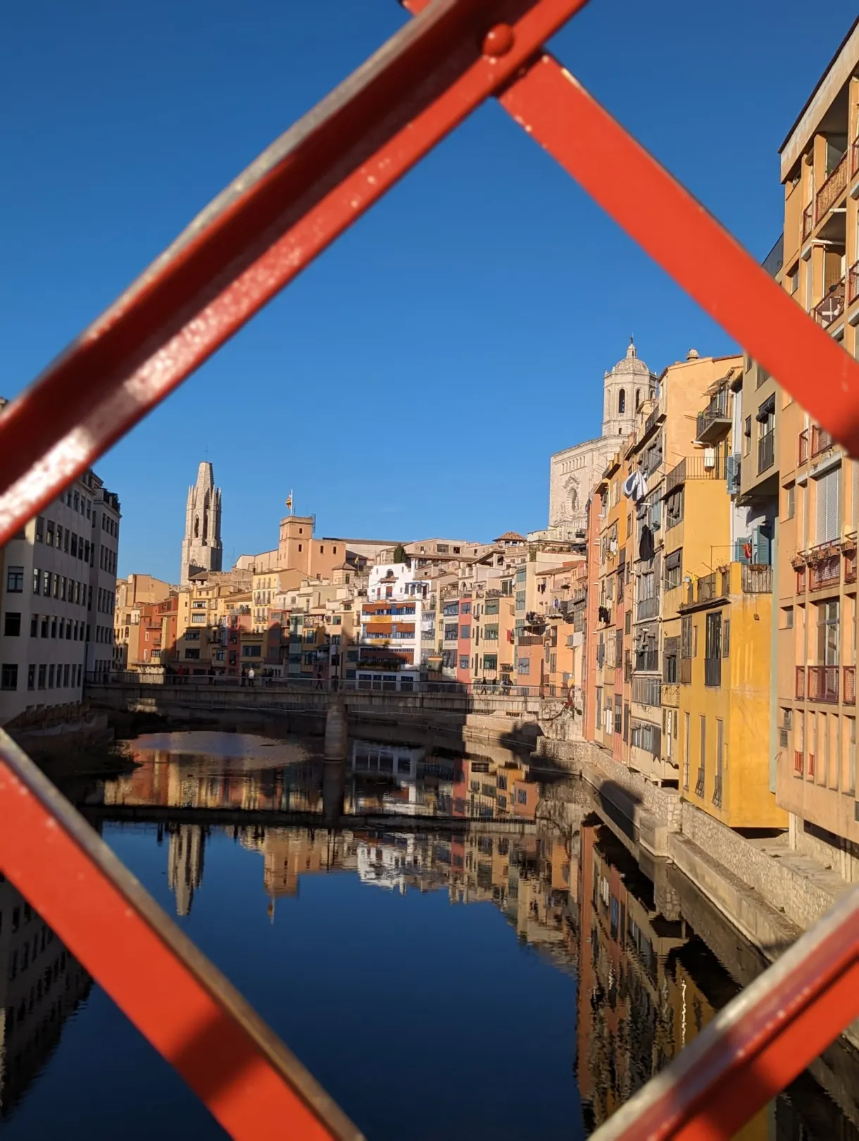 Maisons de l'Onyar cadrées entre les poutrelles rouges d'une passerelle
