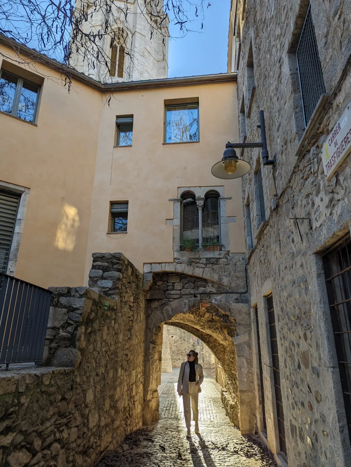 Passante sous une arche de pierre dans une ruelle pavée