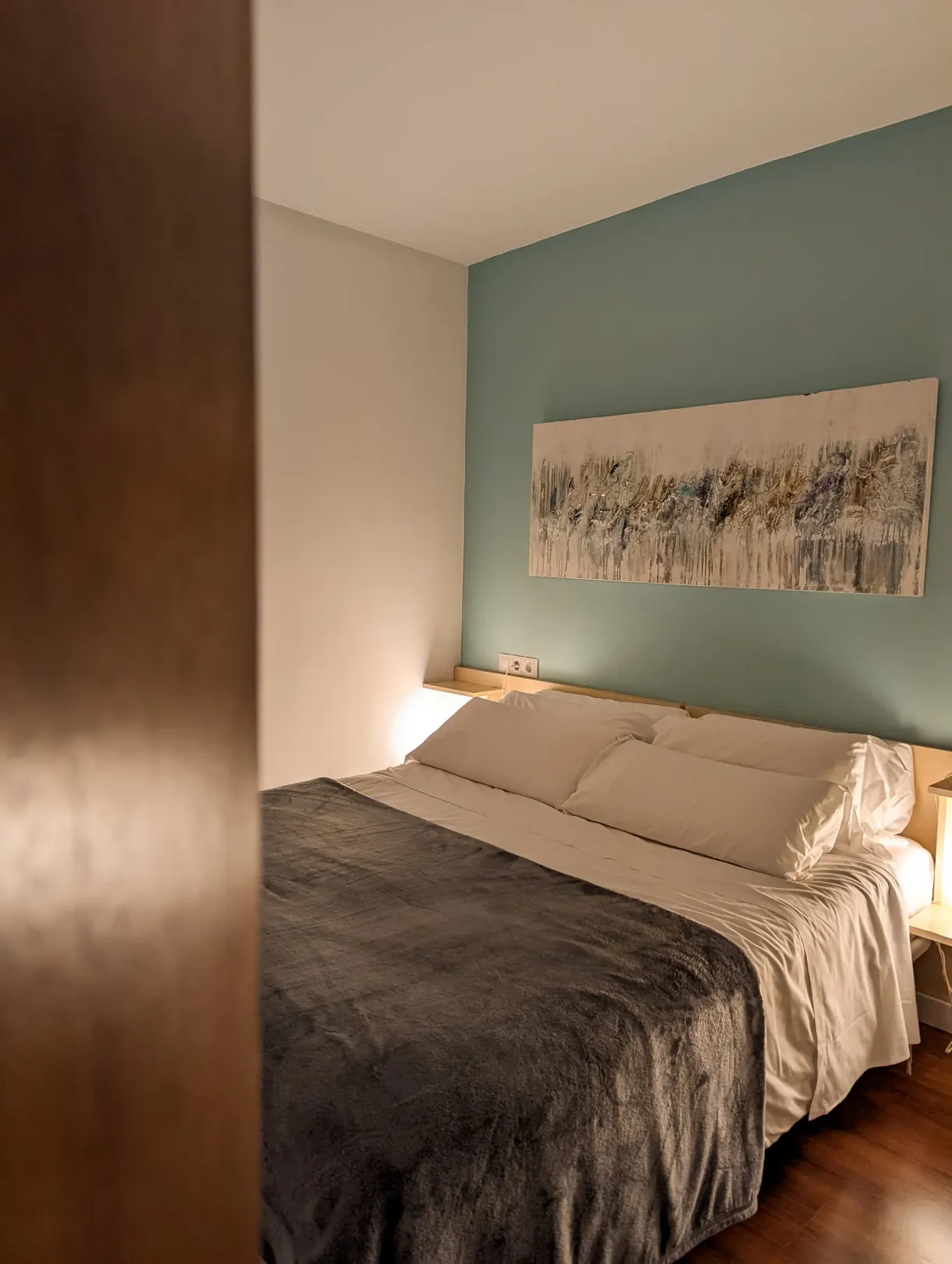 Chambre au mur vert d'eau et grand lit couvert d'un plaid