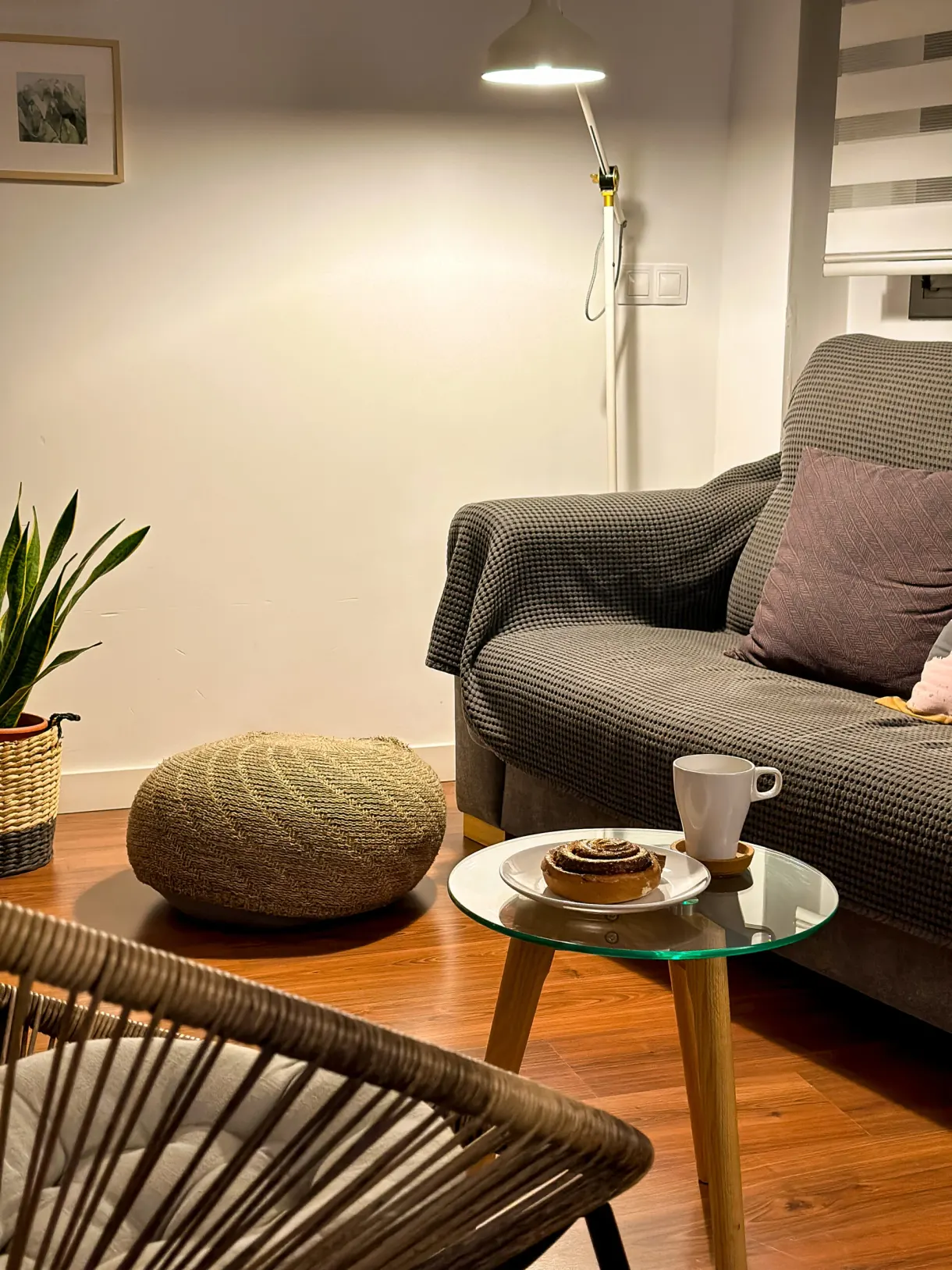 Coin salon avec canapé gris, pouf tressé et café servi