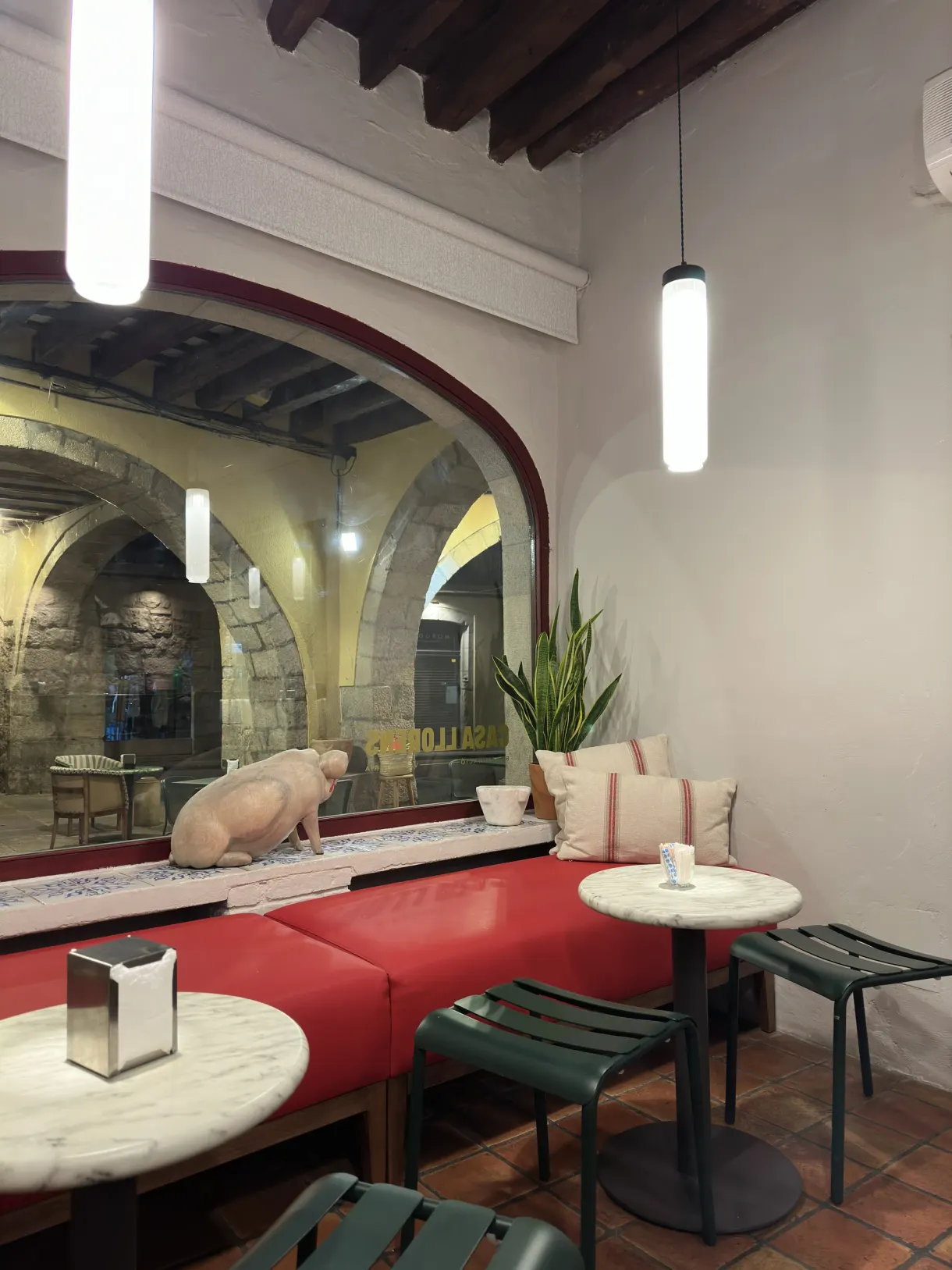 Salle de café aux banquettes rouges et sculpture de cochon en vitrine