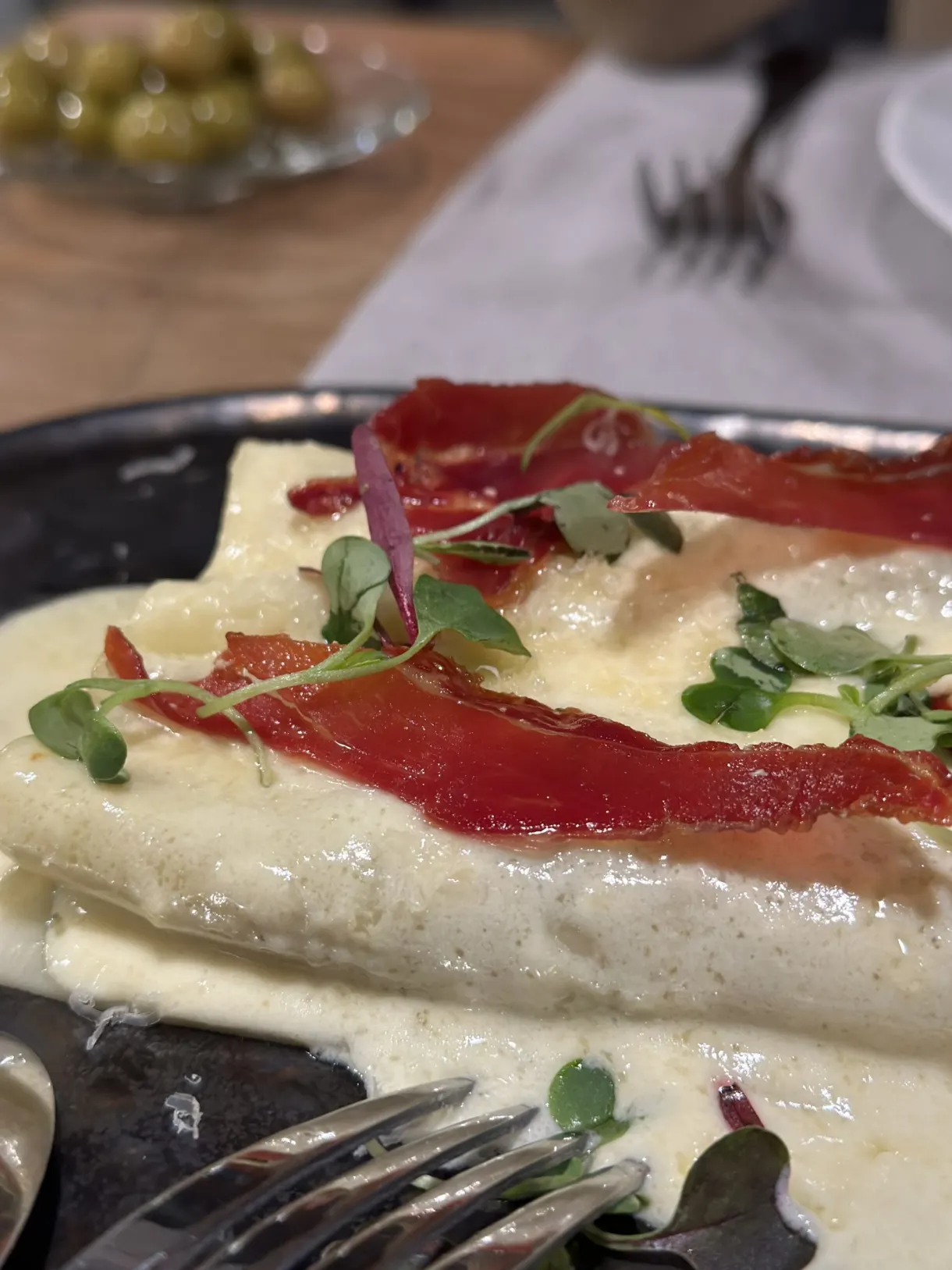 Assiette de pâtes crémeuses garnies de jambon cru et pousses