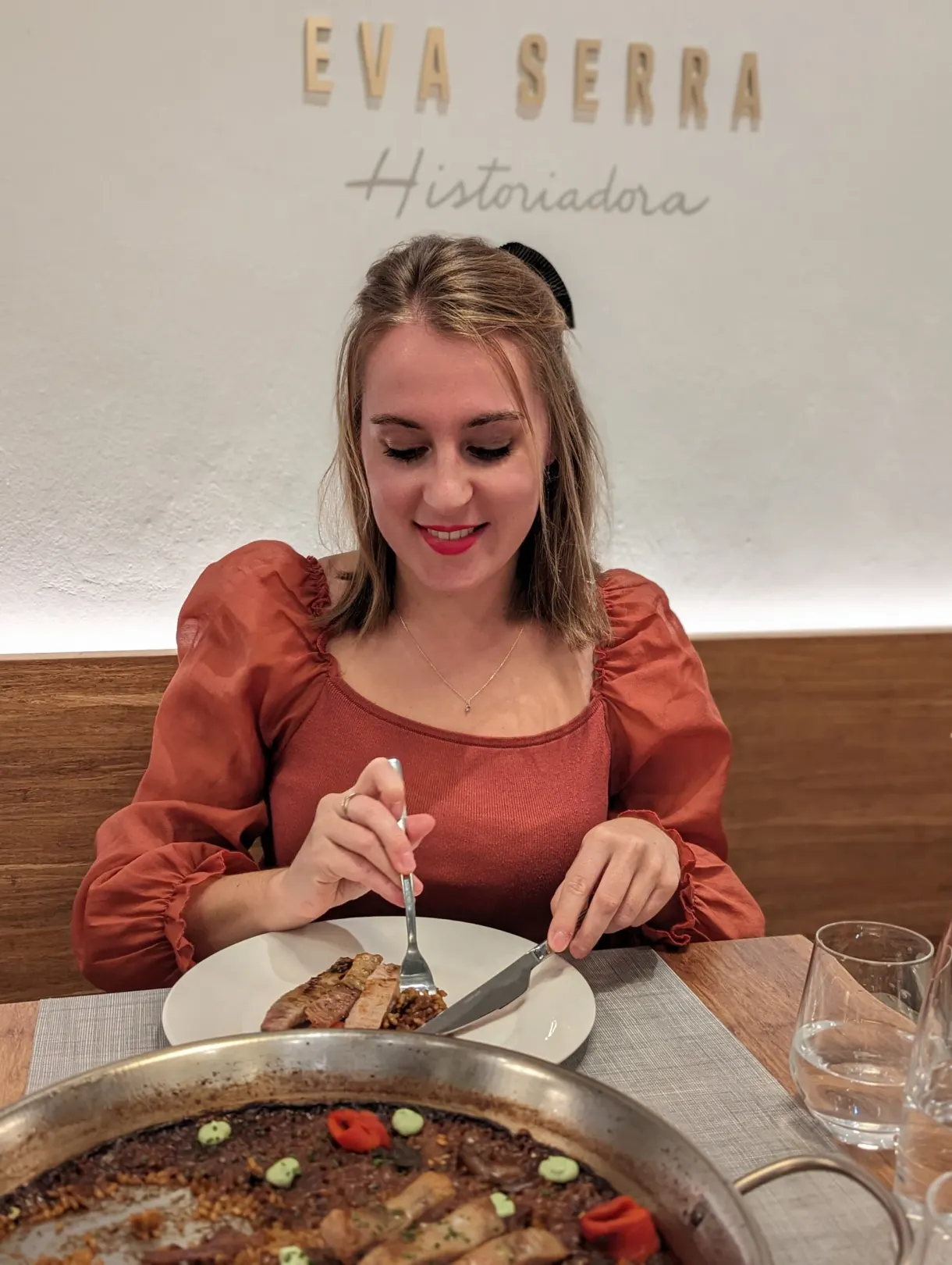 Femme attablée devant une paella servie dans un restaurant
