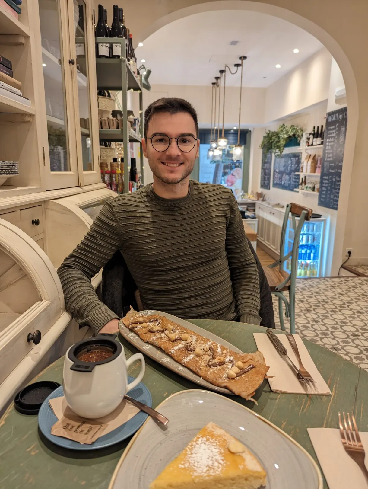 Homme attablé devant une part de tarte et une viennoiserie sucrée