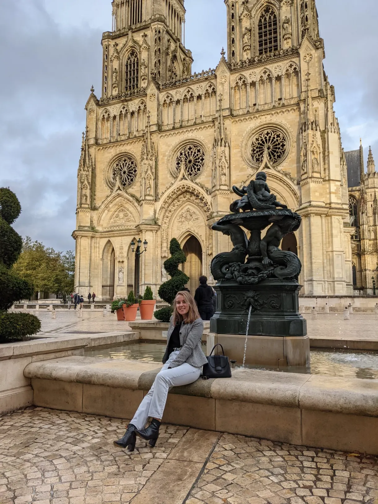 Passante assise sur la fontaine au pied du portail