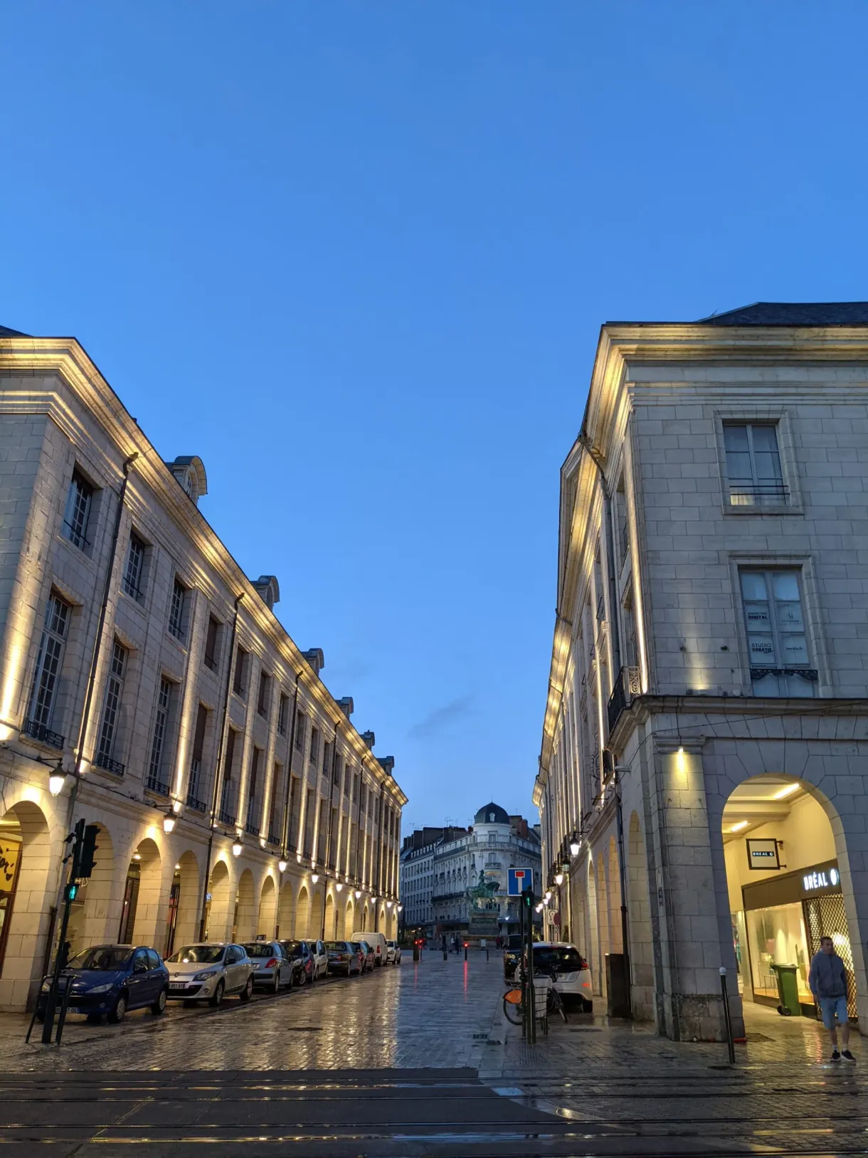 Arcades éclairées le long d'une rue mouillée le soir