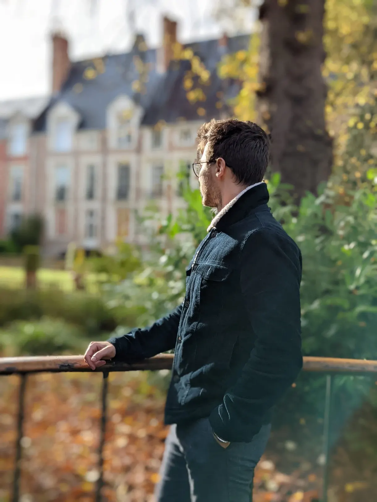Promeneur accoudé à une grille dans un jardin d'automne