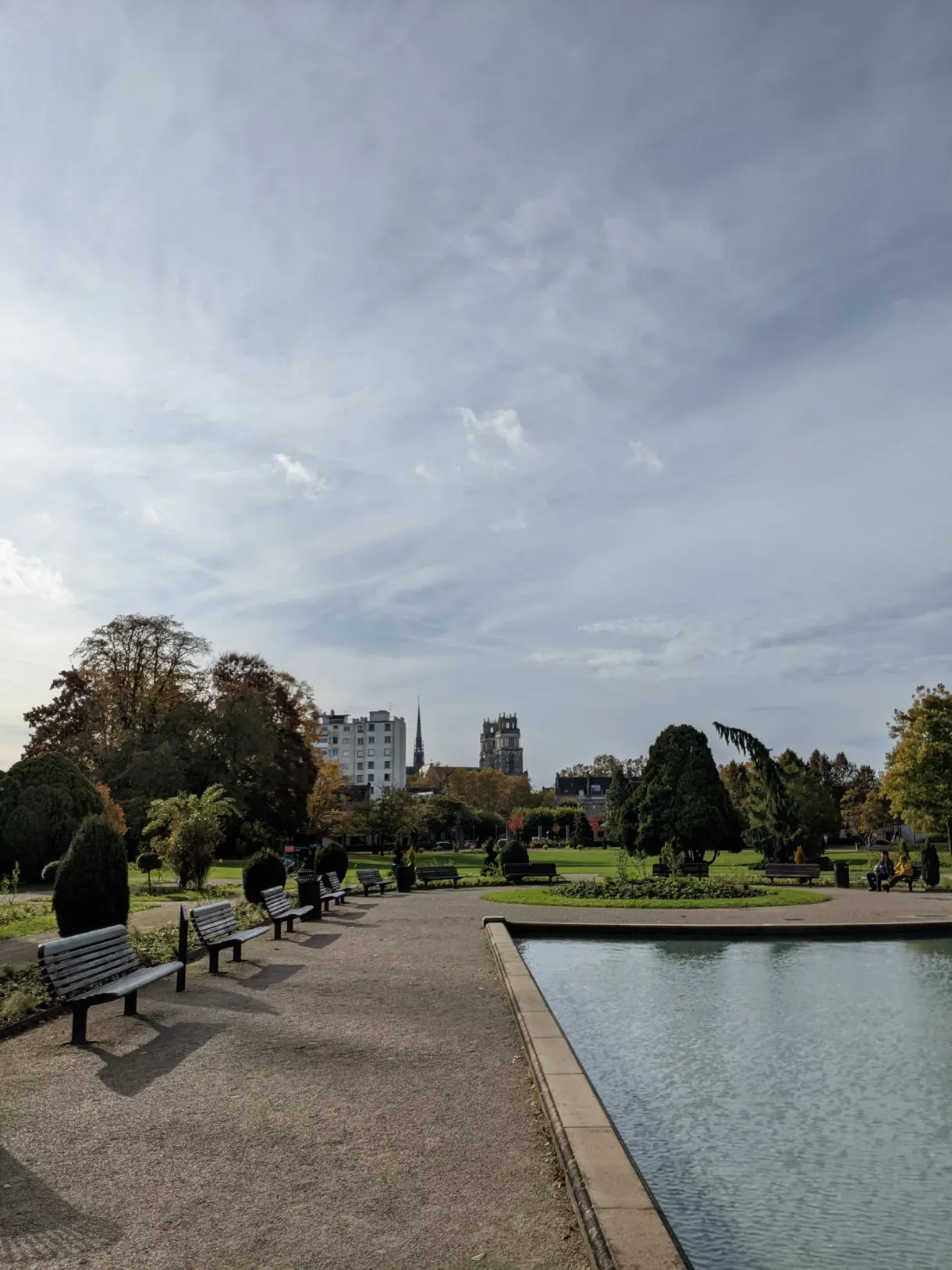 Bassin rectangulaire bordé de bancs et de massifs
