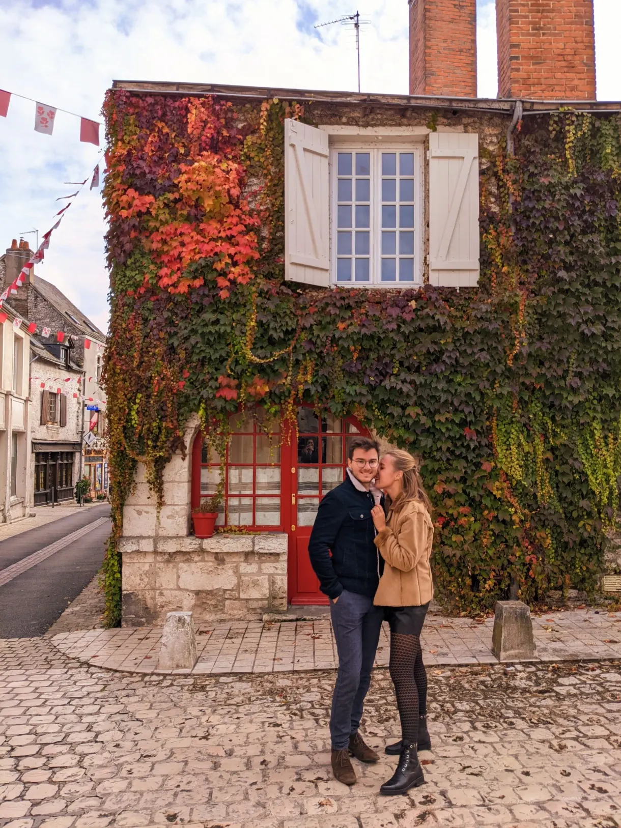 Couple devant une maison tapissée de vigne vierge rouge