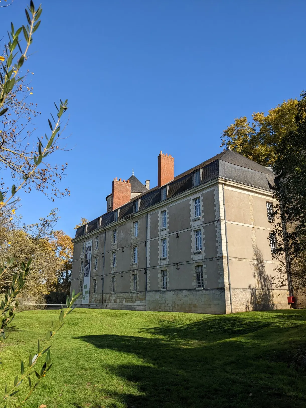 Long bâtiment aux cheminées de brique posé sur une pelouse