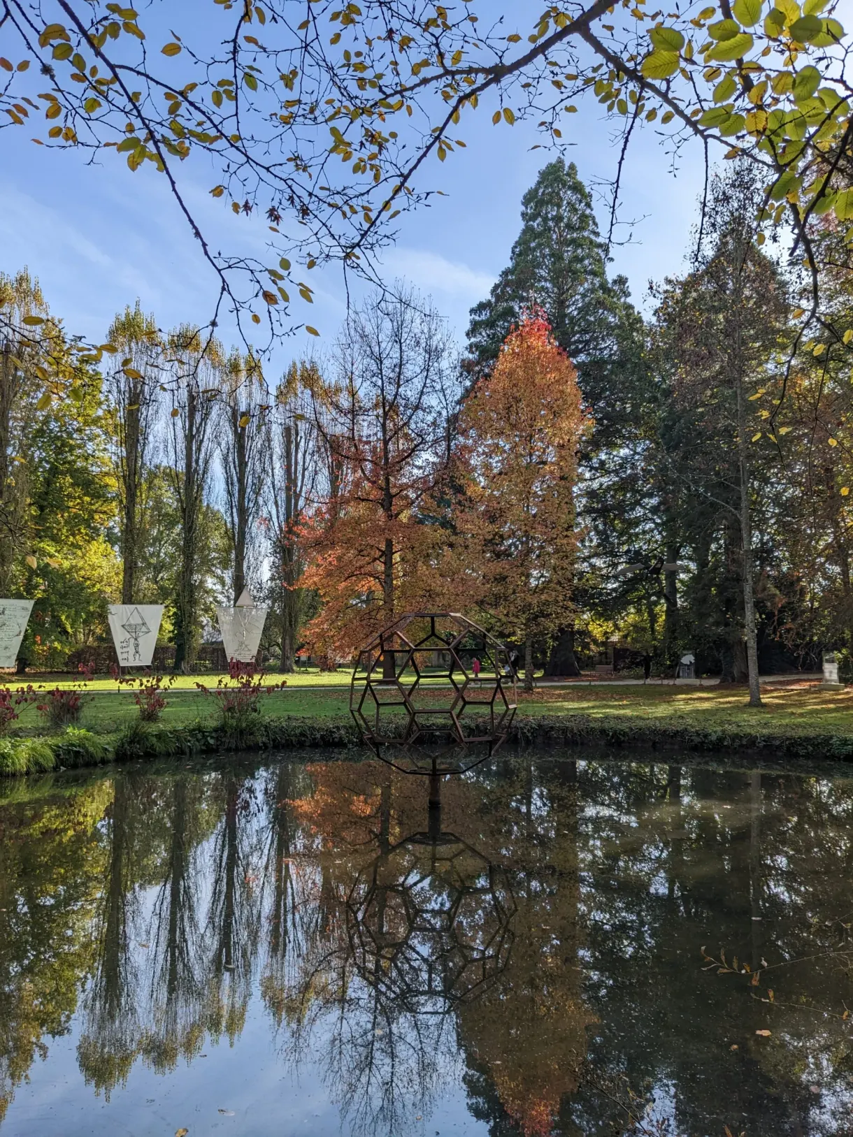 Étang reflétant les arbres d'automne et les sculptures du parc