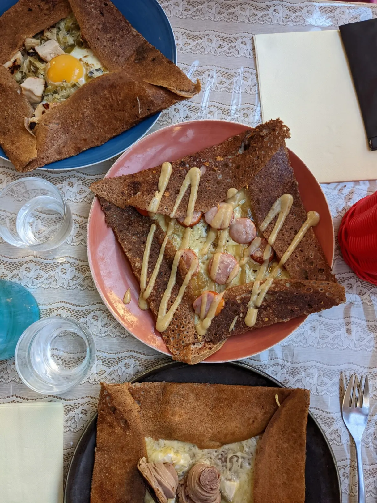 Table de crêperie garnie de galettes complètes et de verres