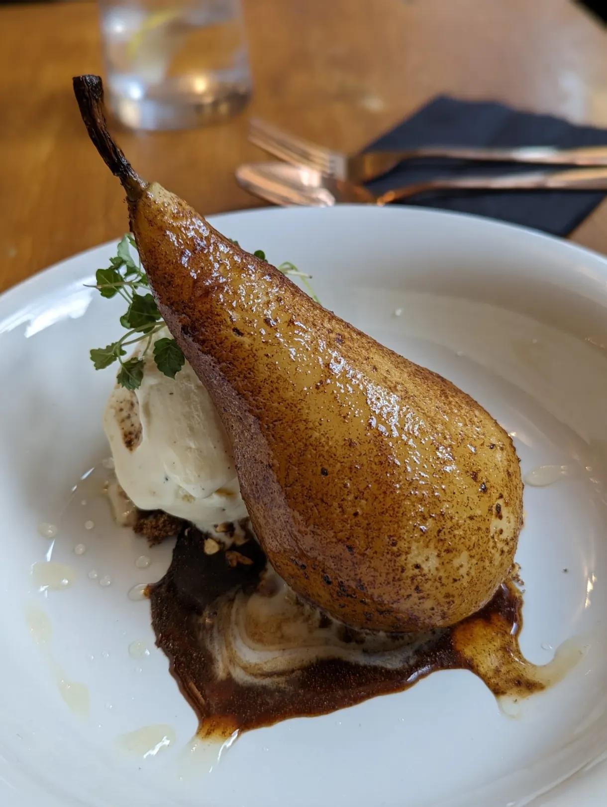 Poire pochée entière servie avec une boule de glace