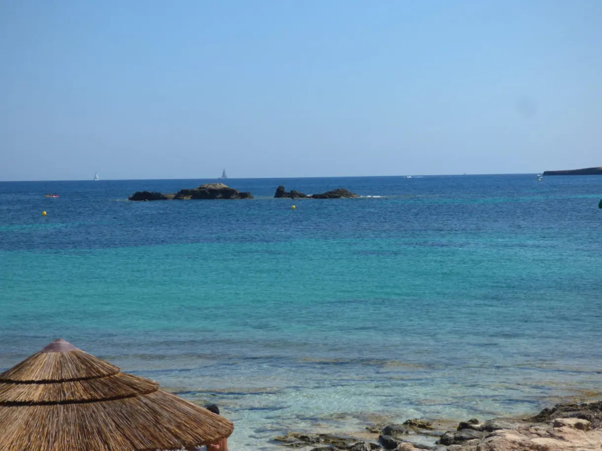 Mer turquoise et îlots vus depuis un parasol de paille