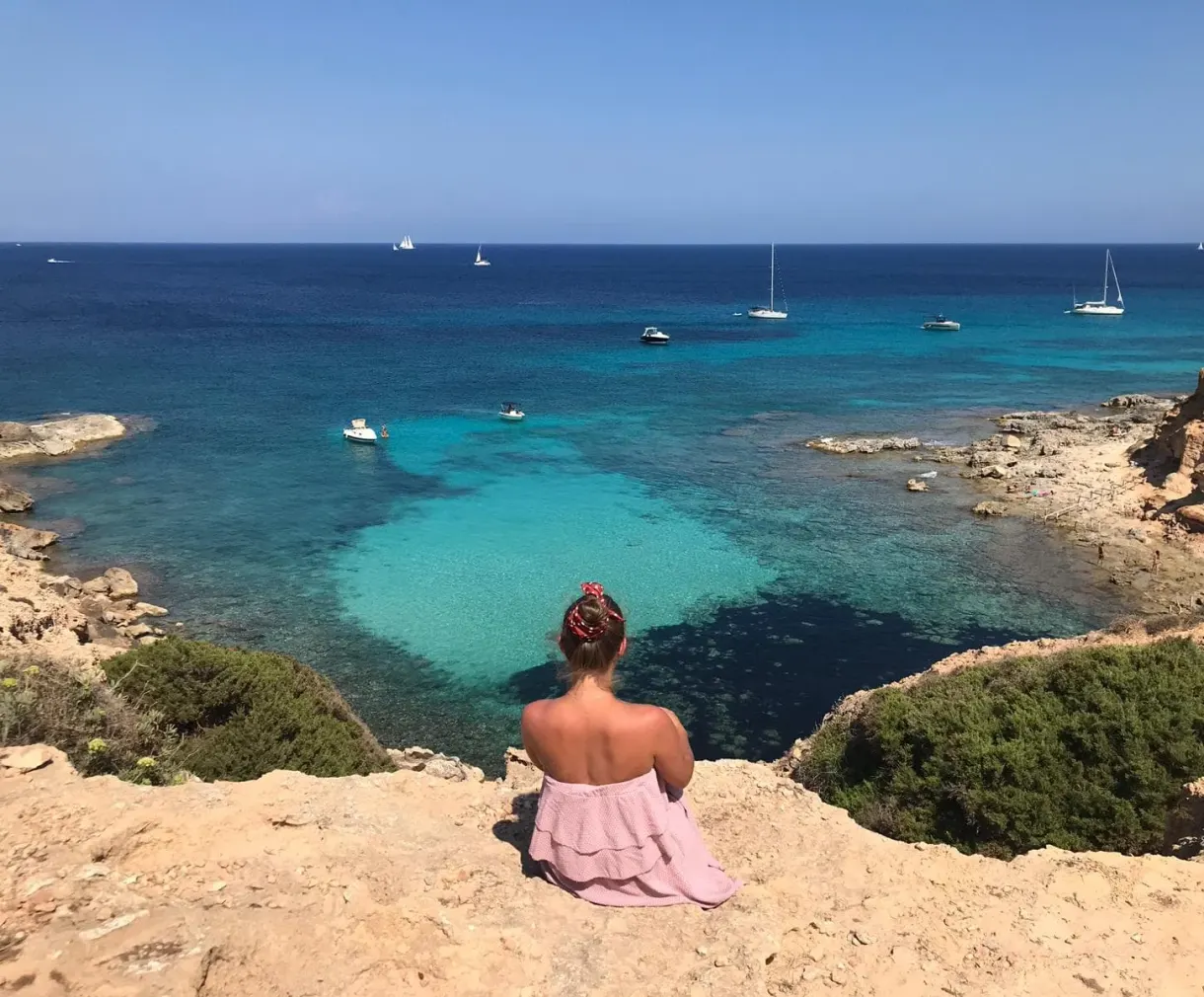Assise au bord de la falaise face à la crique turquoise