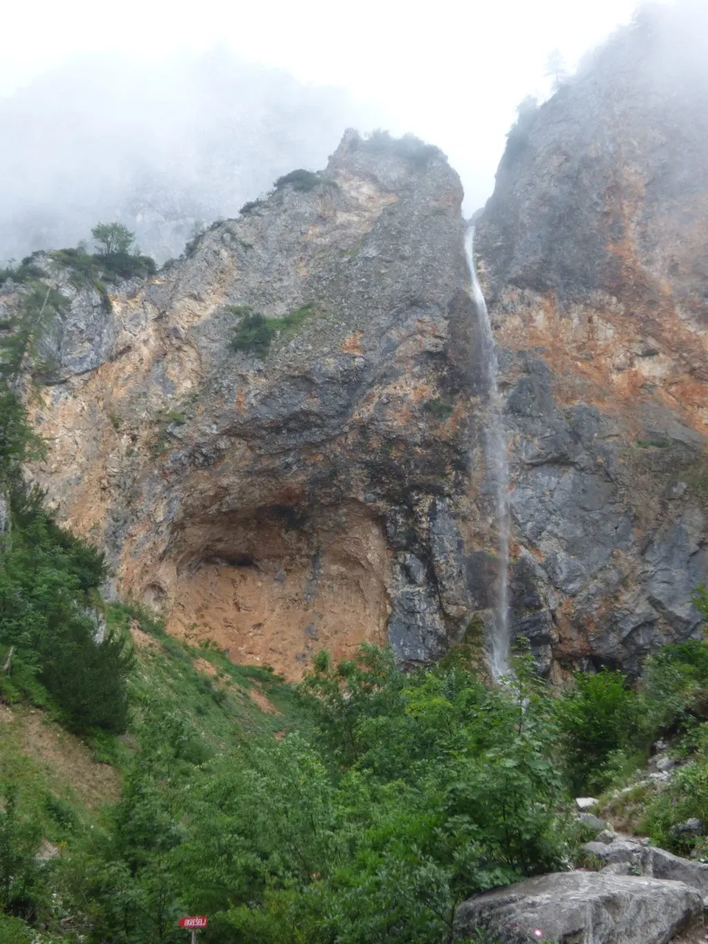Cascade jaillissant d'une haute falaise ocre