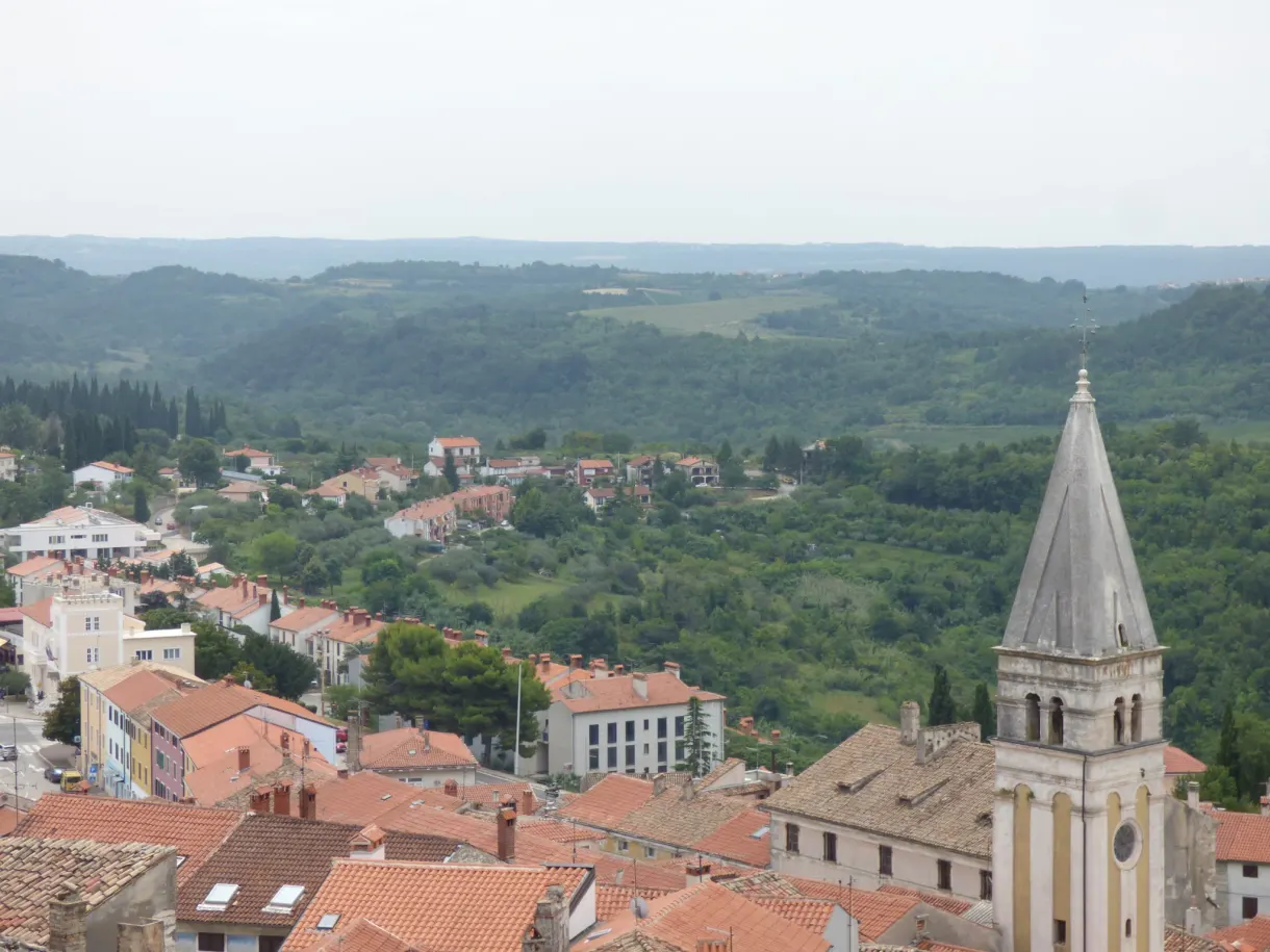 Toits de tuiles et clocher pointu de Buje au milieu des collines
