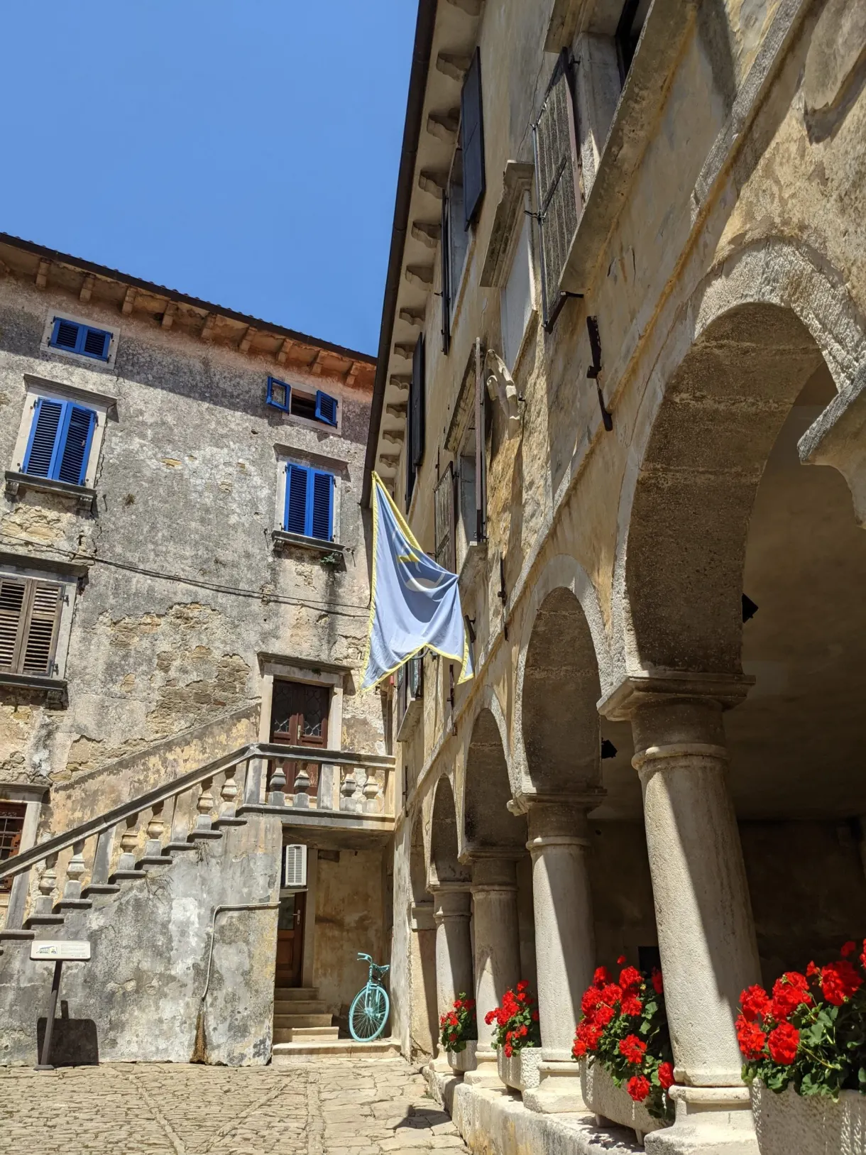 Loggia à arcades et escalier de pierre fleuri de géraniums à Grožnjan