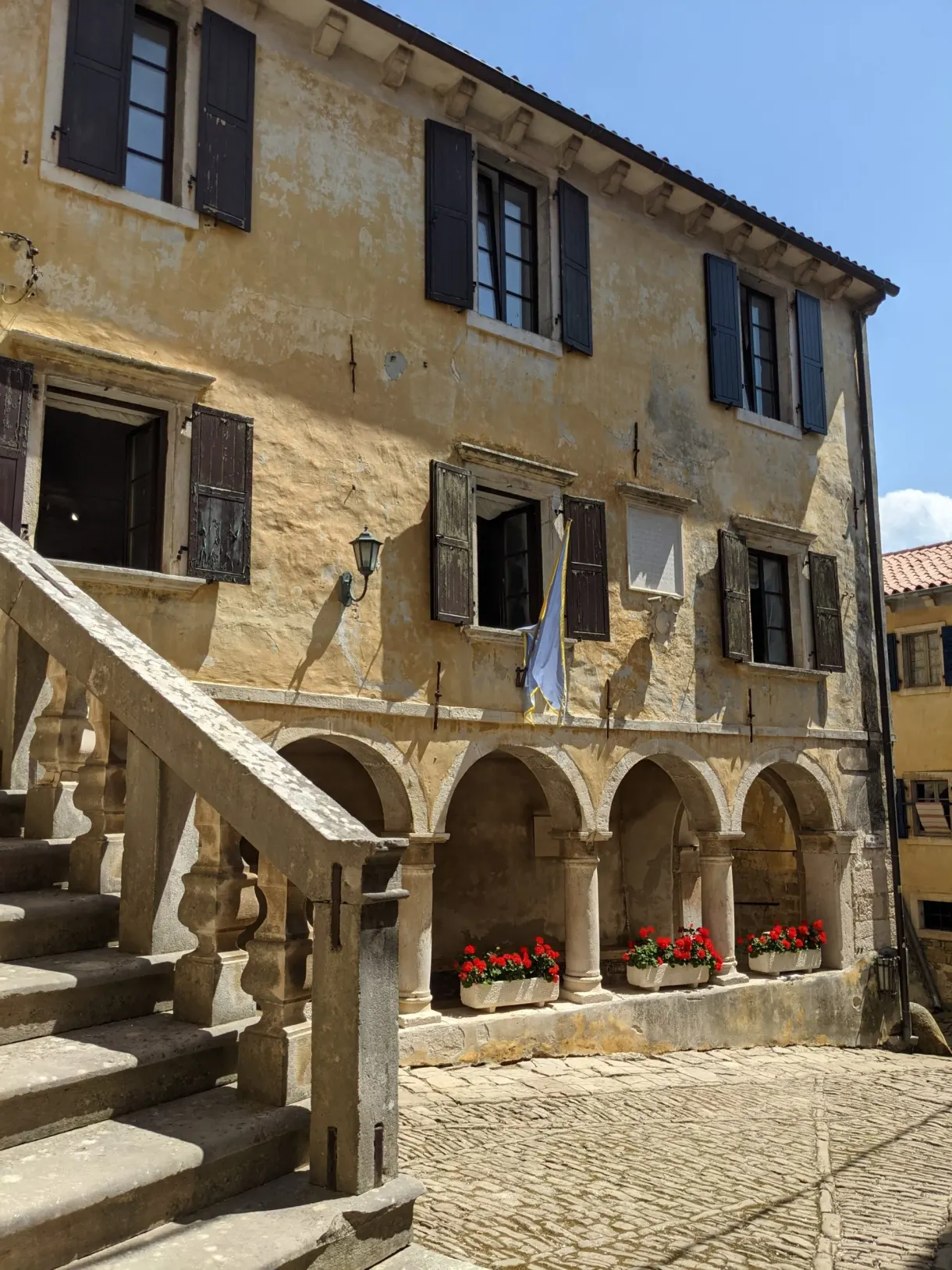 Maison ocre à escalier extérieur et arcades fleuries de Grožnjan