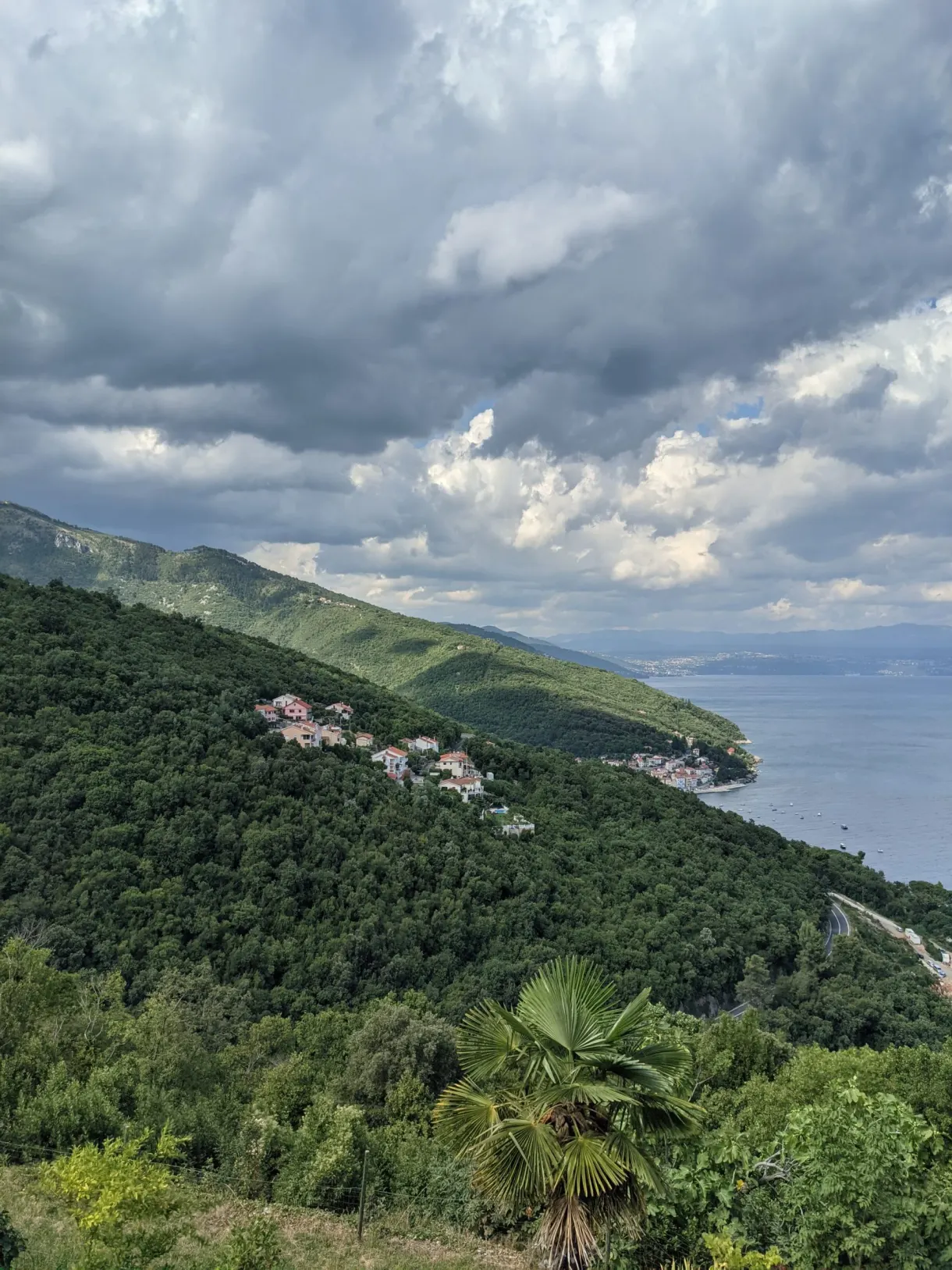 Versant verdoyant descendant vers la mer sous de gros nuages, Mošćenice