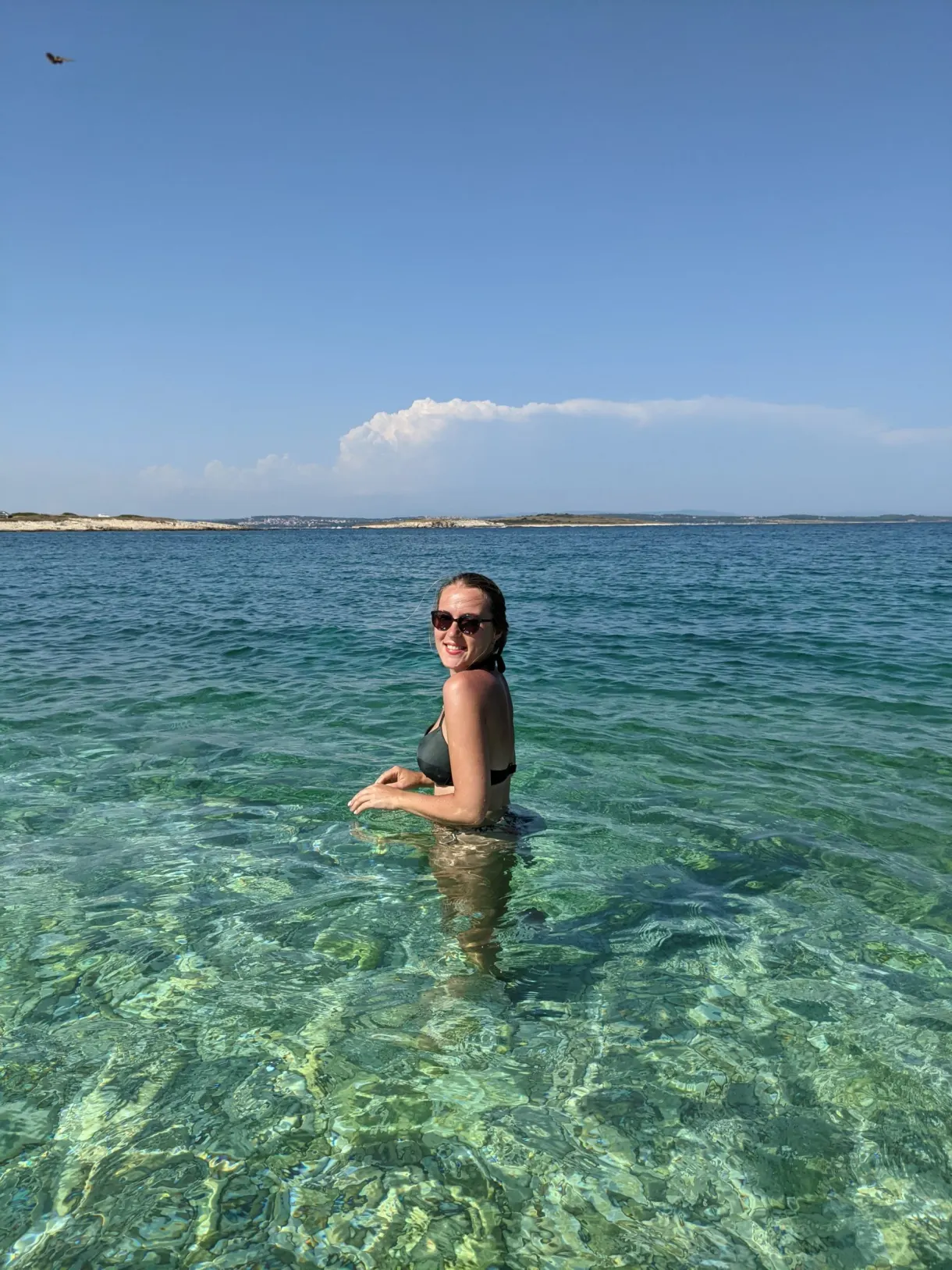 Baigneuse en lunettes de soleil dans l'eau claire de Kamenjak