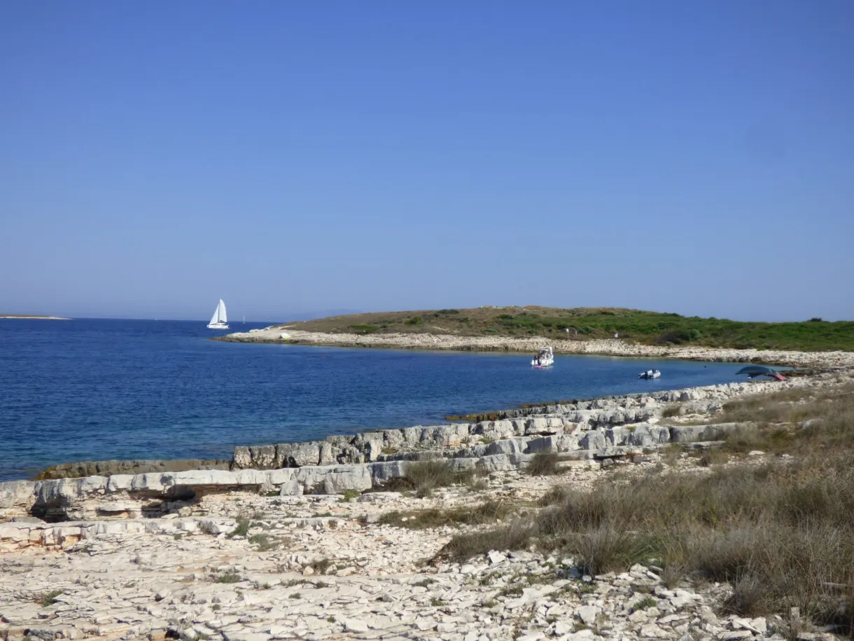 Littoral plat et rocailleux de Kamenjak, voilier au large