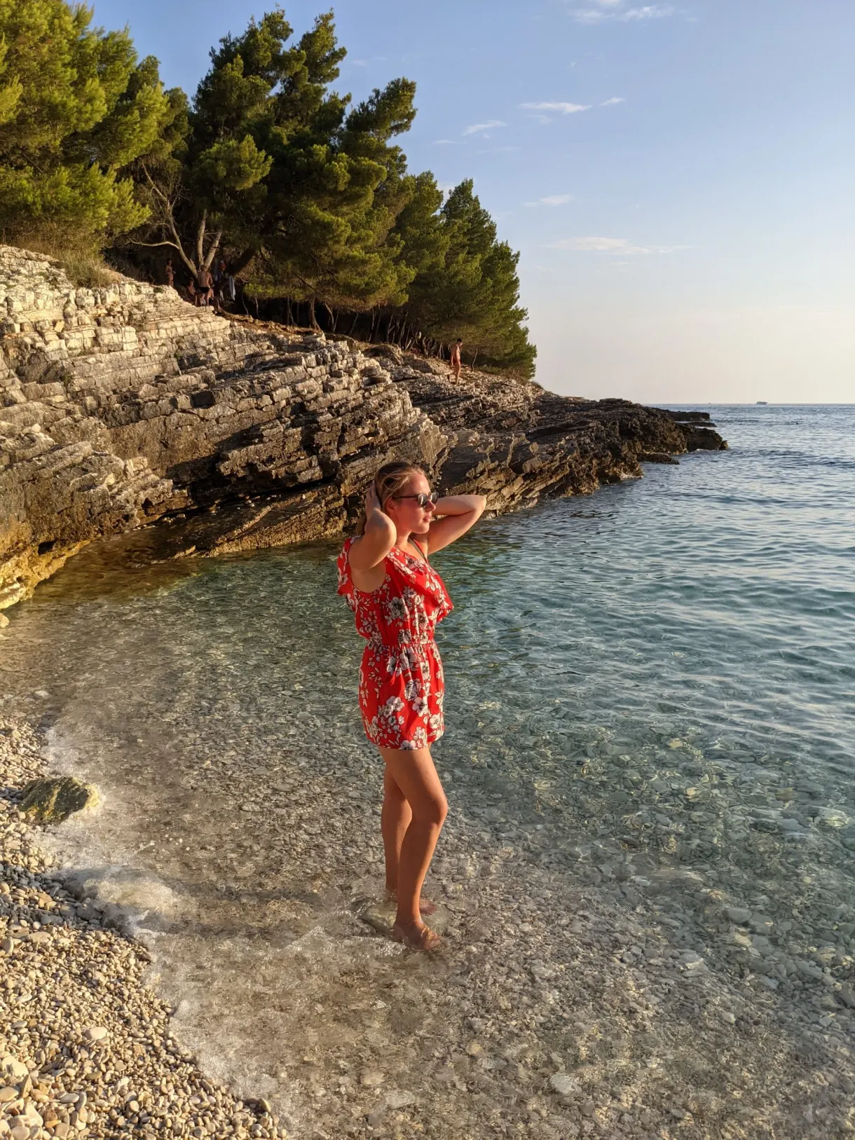 Femme en robe à fleurs sur une plage de galets de Kamenjak
