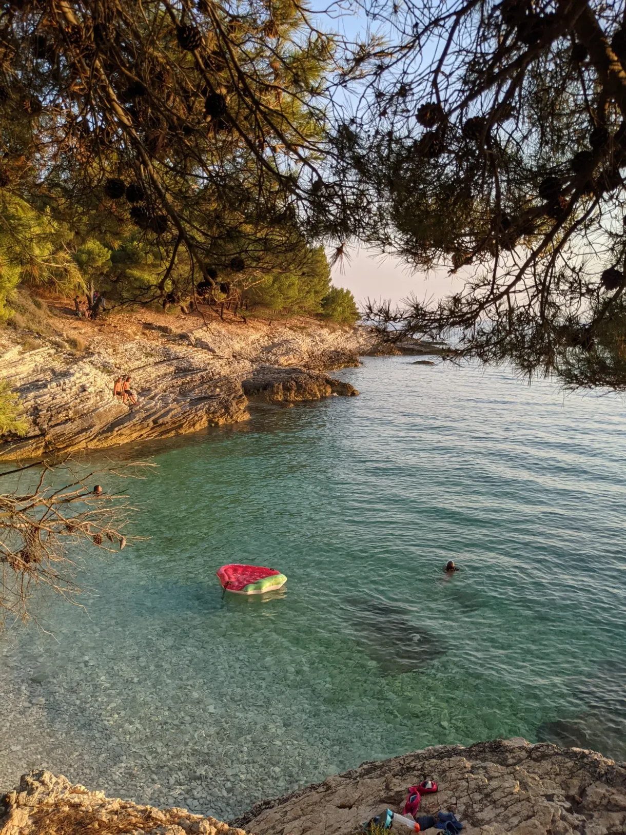 Bouée gonflable rouge dans une crique turquoise ombragée de pins