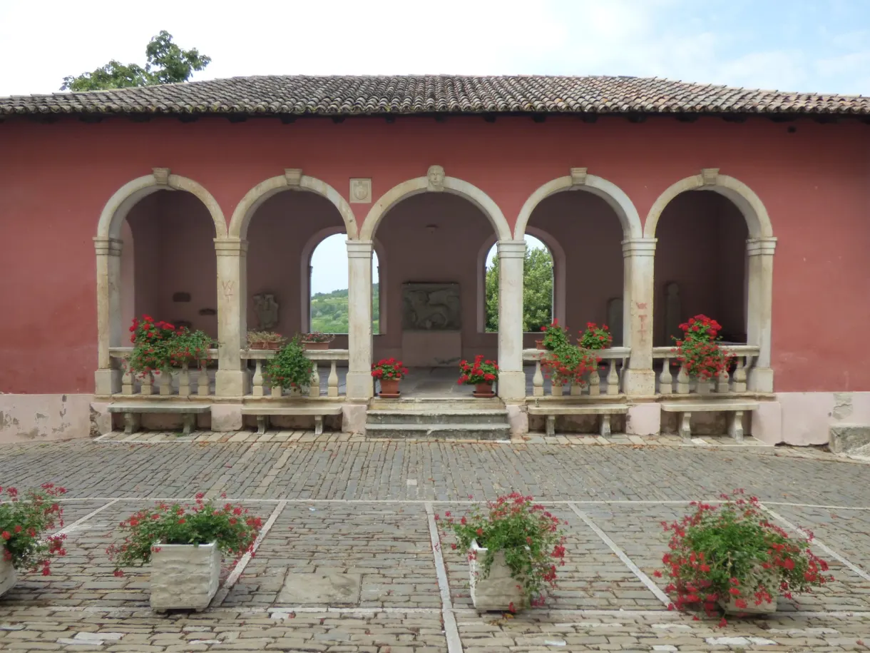 Loggia rose à arcades et pots de géraniums sur une place d'Oprtalj