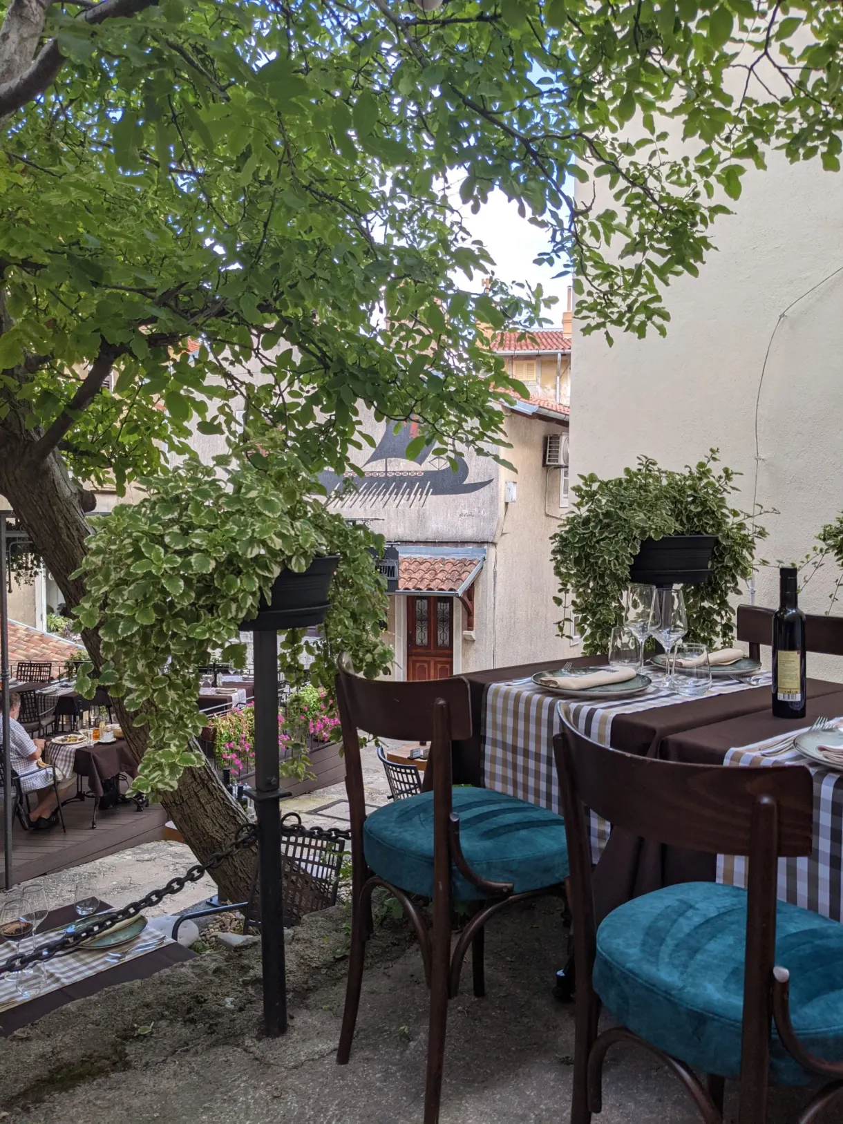 Terrasse de restaurant aux chaises turquoise dominant les toits du village