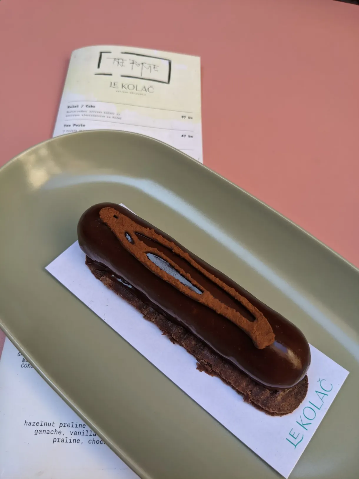 Éclair au chocolat sur un plateau vert à côté de la carte des desserts